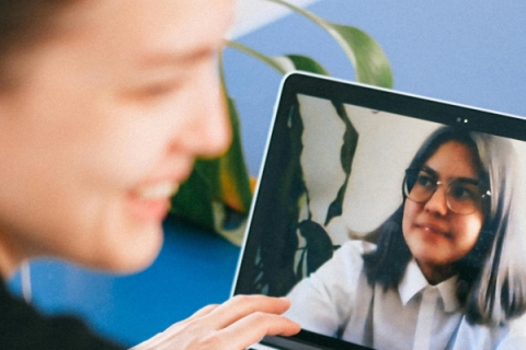Foto eines Videocalls: Person vor Laptop auf dem eine Gesprächspartnerin sichtbar ist