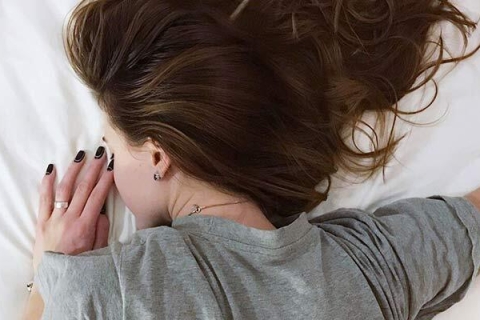 Foto einer jungen Frau, die schlaflos in ihrem Bett liegt.